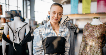 Fashion designer Meg Fletcher stands in front of her designs at an event