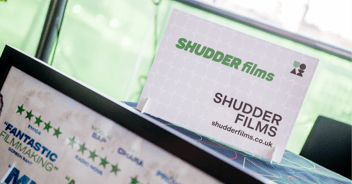 A Shudder Films sign sits on top of a display at an exhibition